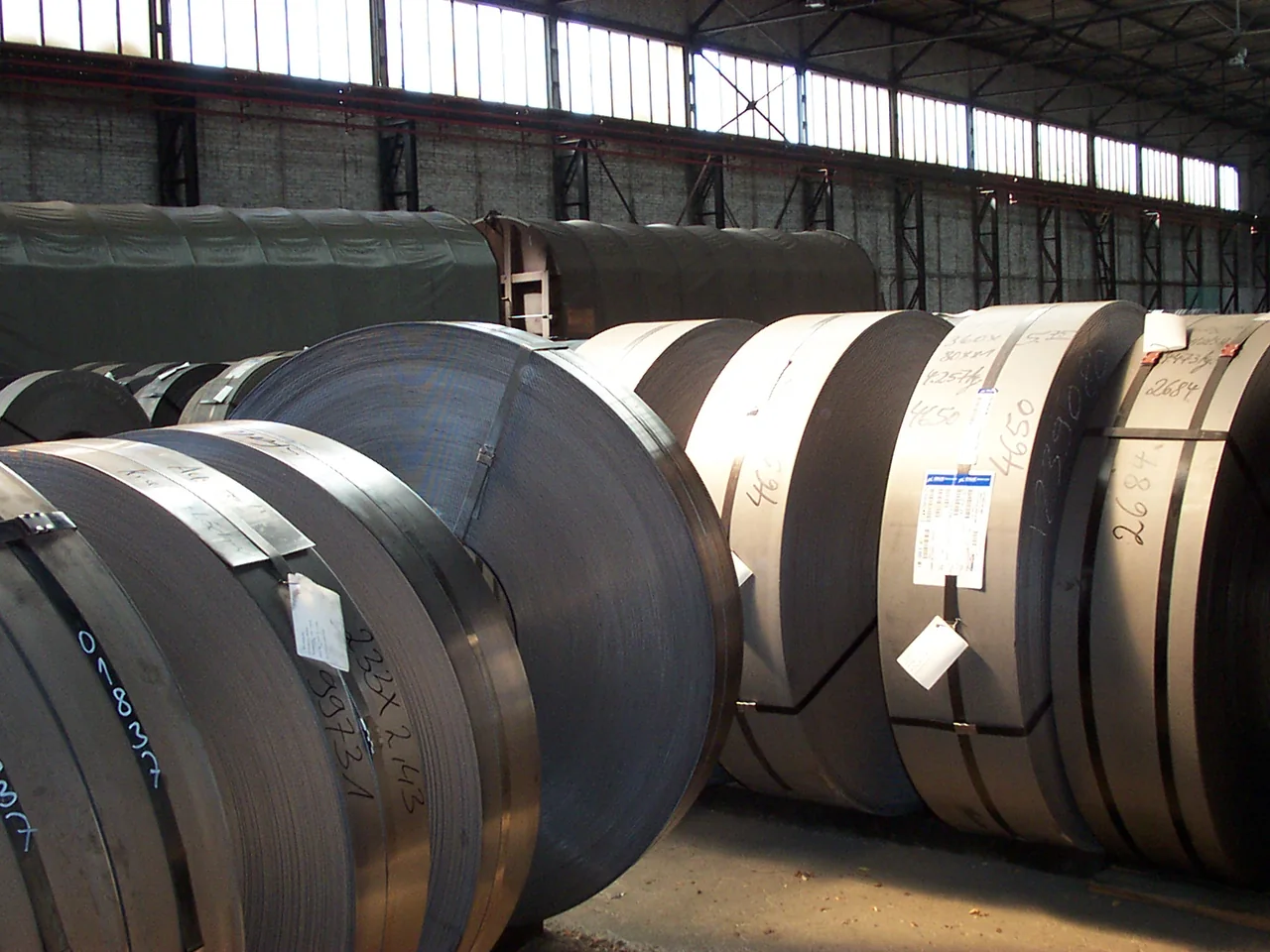 Bulk hot-rolled steel coils stored in an industrial warehouse