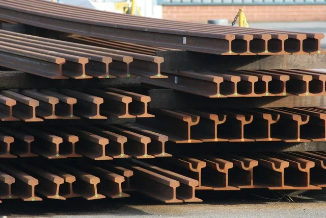 Rows of stacked steel rails in a rail stockyard